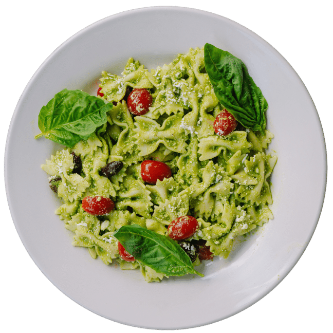 Bow Tie pesto salad with cherry tomatoes on a white round plate